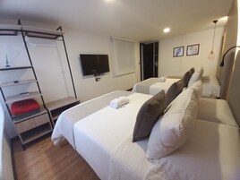 Habitación de hotel con dos camas, un televisor, un estante con toallas y una puerta con el número 201.