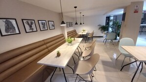 A modern dining area with a long bench, several tables, and chairs. - HOTEL SANTORI (San Juan de Pasto)