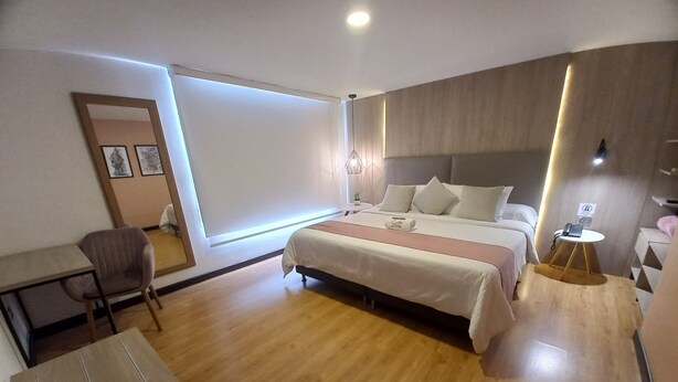 A modern hotel room with a large bed, a desk, a chair, and a small table with a phone. - HOTEL SANTORI (San Juan de Pasto)