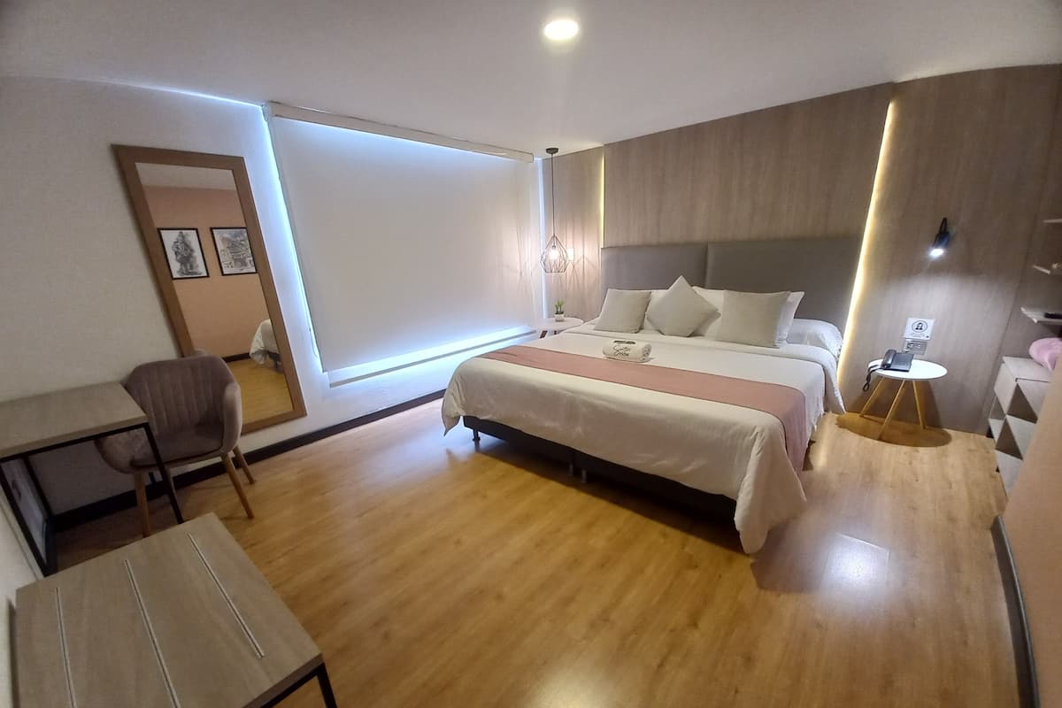 Une chambre d’hôtel moderne, dotée d’un grand lit, d’un bureau, d’une chaise et d’une petite table avec un téléphone.