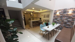 A modern kitchen with a central island, light blue chairs, and a dining table. - HOTEL SANTORI (San Juan de Pasto)