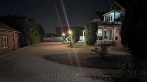Une allée pavée mène à une maison dotée d’un porche et d’un petit jardin.