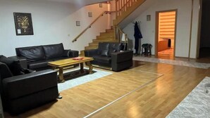 Un vaste salon doté d’un plancher en bois, d’un escalier et offrant une vue sur l’extérieur.