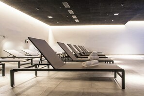 Uma sala de spa moderna com várias mesas de massagem, cada uma equipada com uma toalha e um apoio para a cabeça.