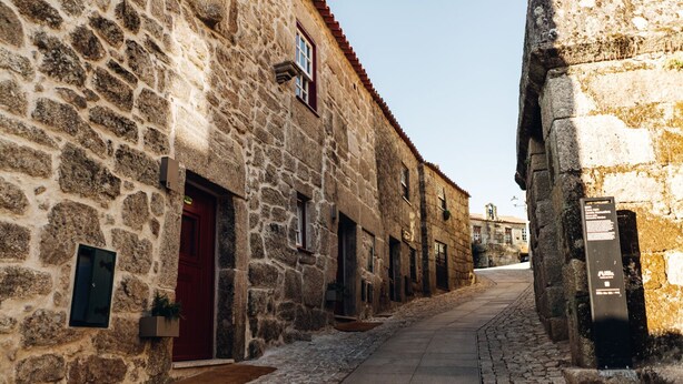 A narrow stone street flanked by historic buildings with red doors and small windows. - a beautiful 22 m2 studio flat (Sortelha)