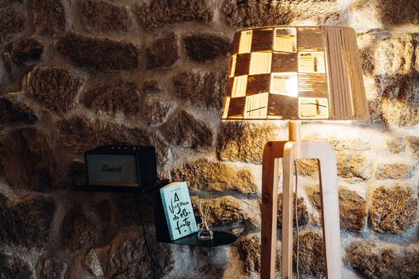 A stone wall with a radio, a book, and a lamp.