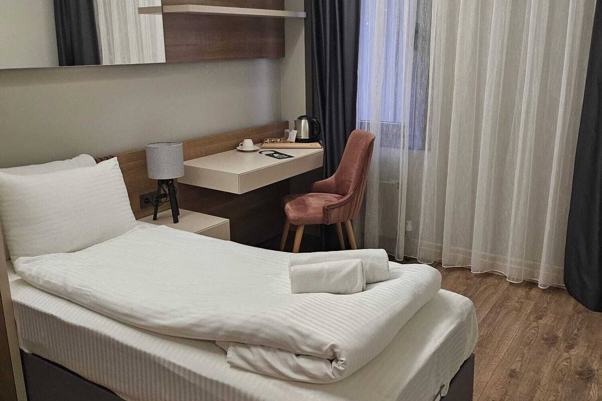 Une chambre d’hôtel avec un grand lit, un bureau, une chaise et une fenêtre avec des rideaux.