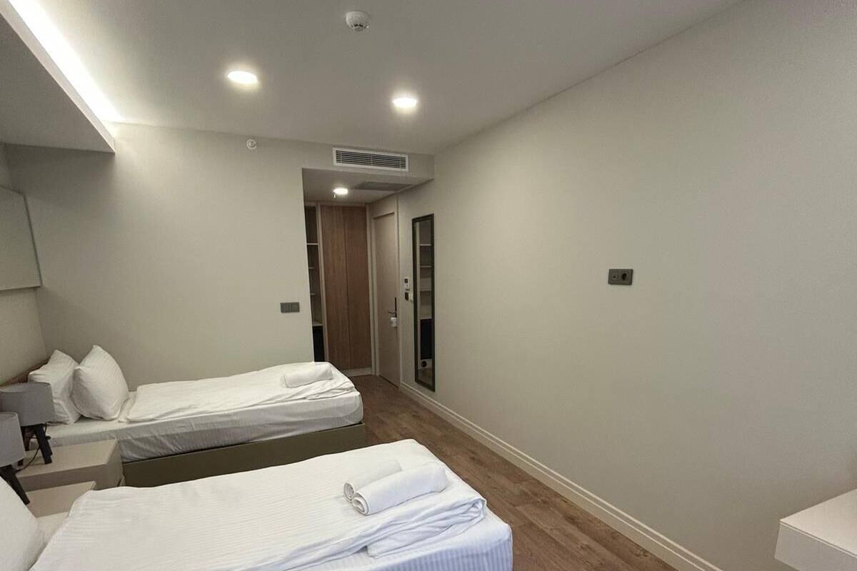 Une chambre d’hôtel avec deux lits, une table de chevet avec une lampe, une armoire et une porte de salle de bain.