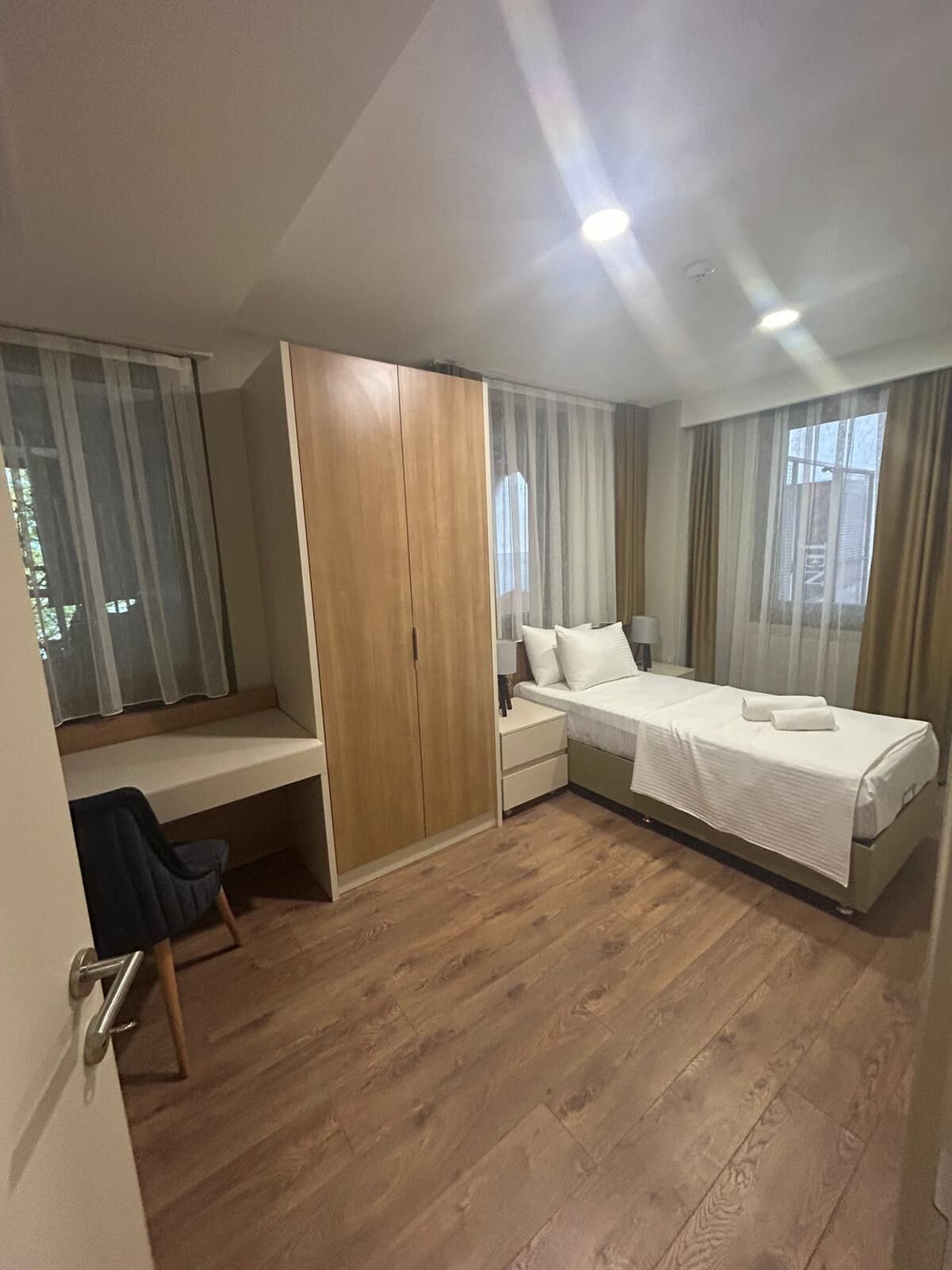 A hotel room with a bed, a desk, a chair, and a wardrobe.