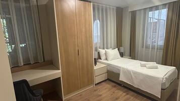 A hotel room with a bed, a desk, a chair, and a wardrobe.
