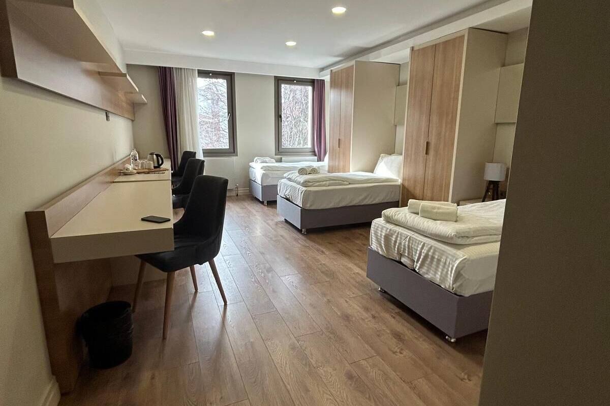 Une chambre d’hôtel moderne équipée d’un bureau, de deux lits et d’une armoire.