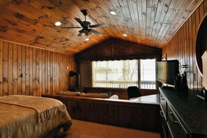 Cozy cabin-style room with a bed, television, and bench.
