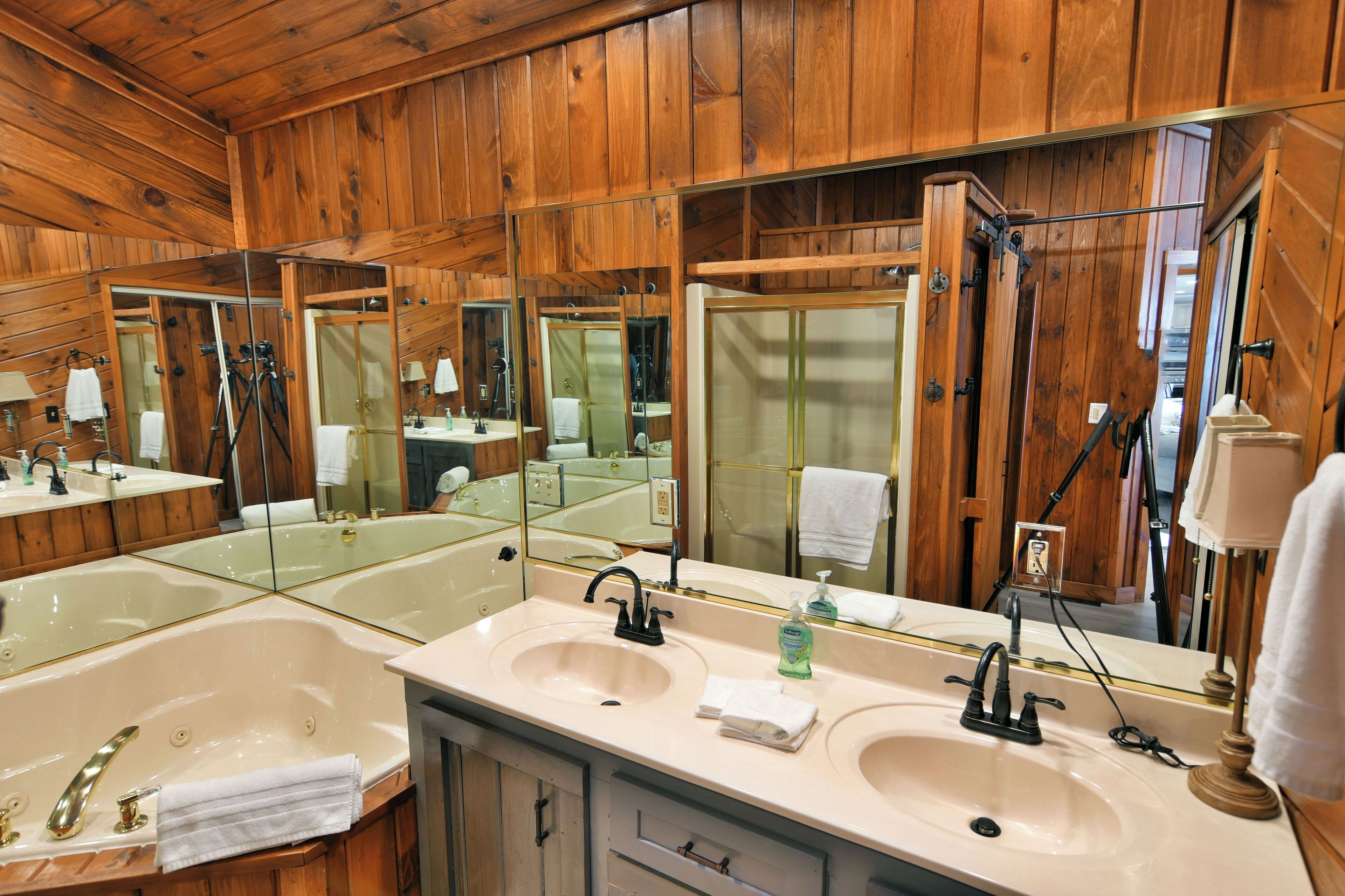 A wooden-paneled bathroom with two sinks, mirrors, and a shower.