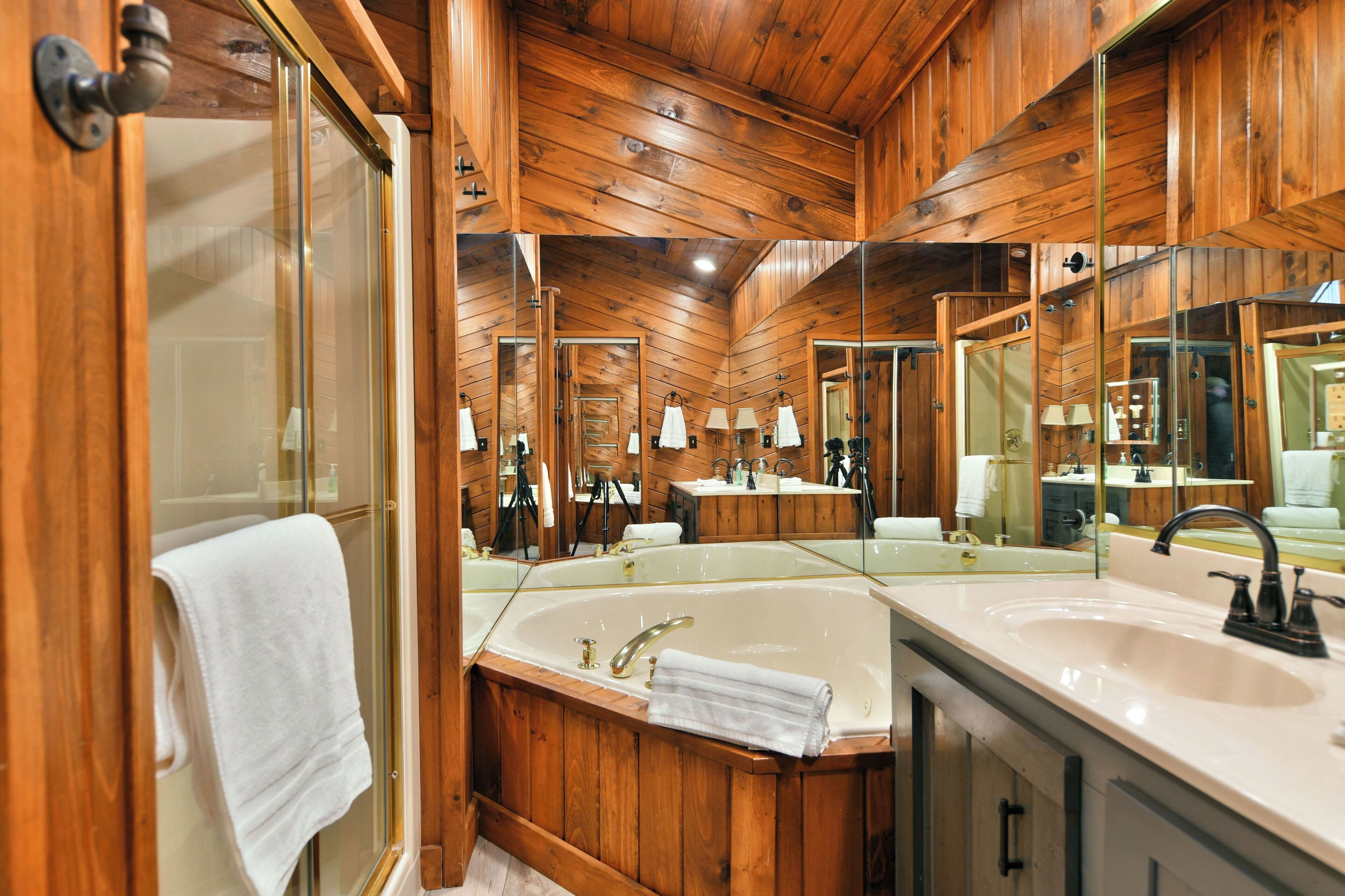 Une salle de bain rustique, avec des murs en bois, un grand miroir, une baignoire et un lavabo.