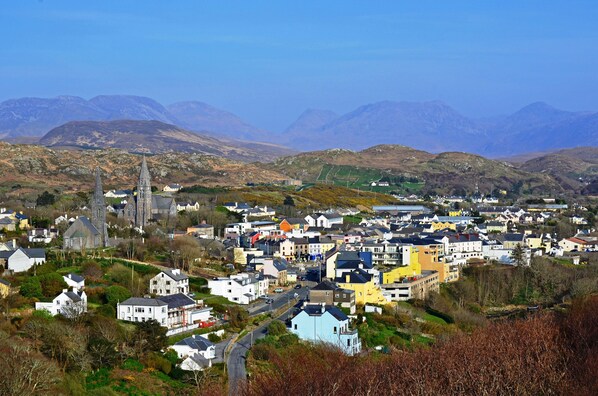 A town with a prominent church, residential buildings, and a mountainous backdrop. - Beautiful house in stunning Ballyconneely Connemara (Clifden)