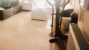 A spacious living room with a large window, a treadmill, a sofa, and a television. - Modern Lux Apt by Acropolis I Private Parking, Gym, Balcony, Metro 1-min Walk (Athina)
