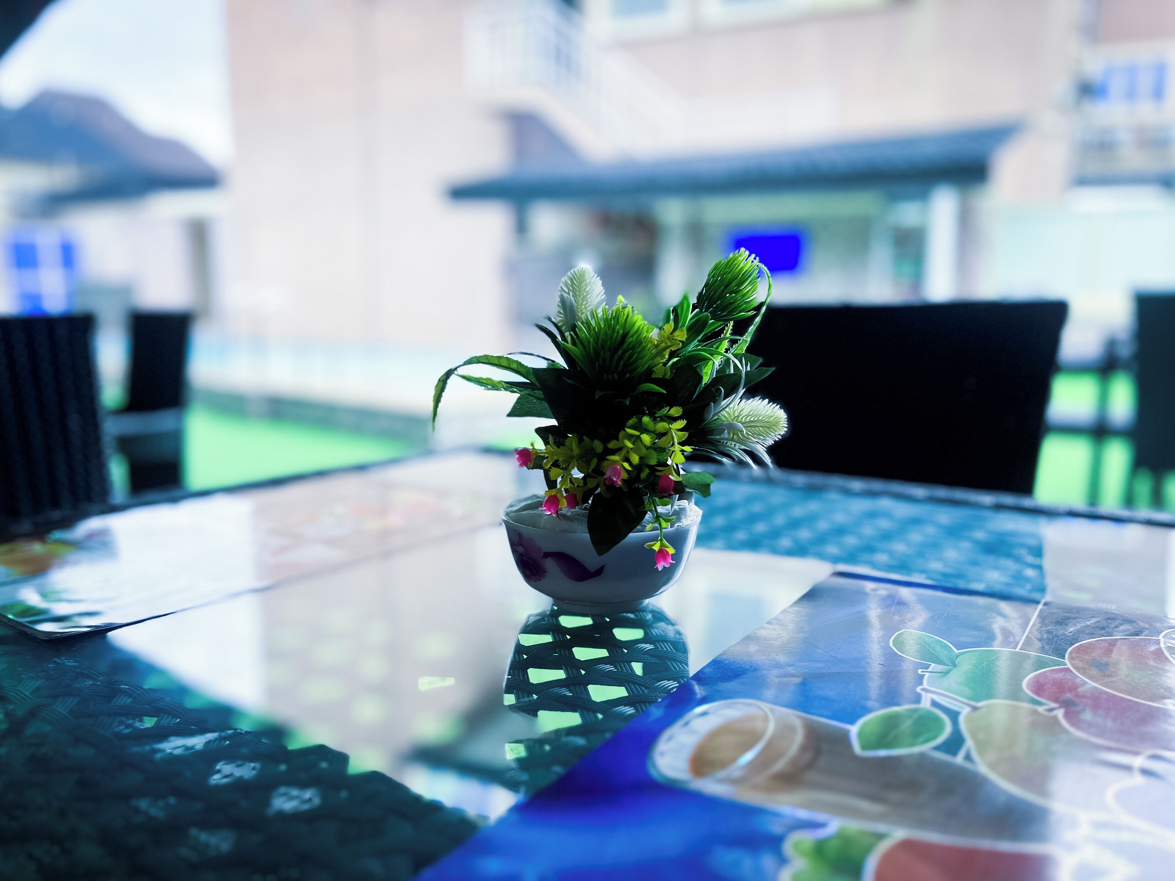 A glass table with a potted plant and a rolled-up menu.