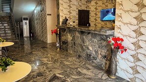 A hotel lobby with a marble reception desk, a flat-screen TV, a staircase, and a reception area with a sign. - Mo-House Hotels and Events Centre (Abuja)