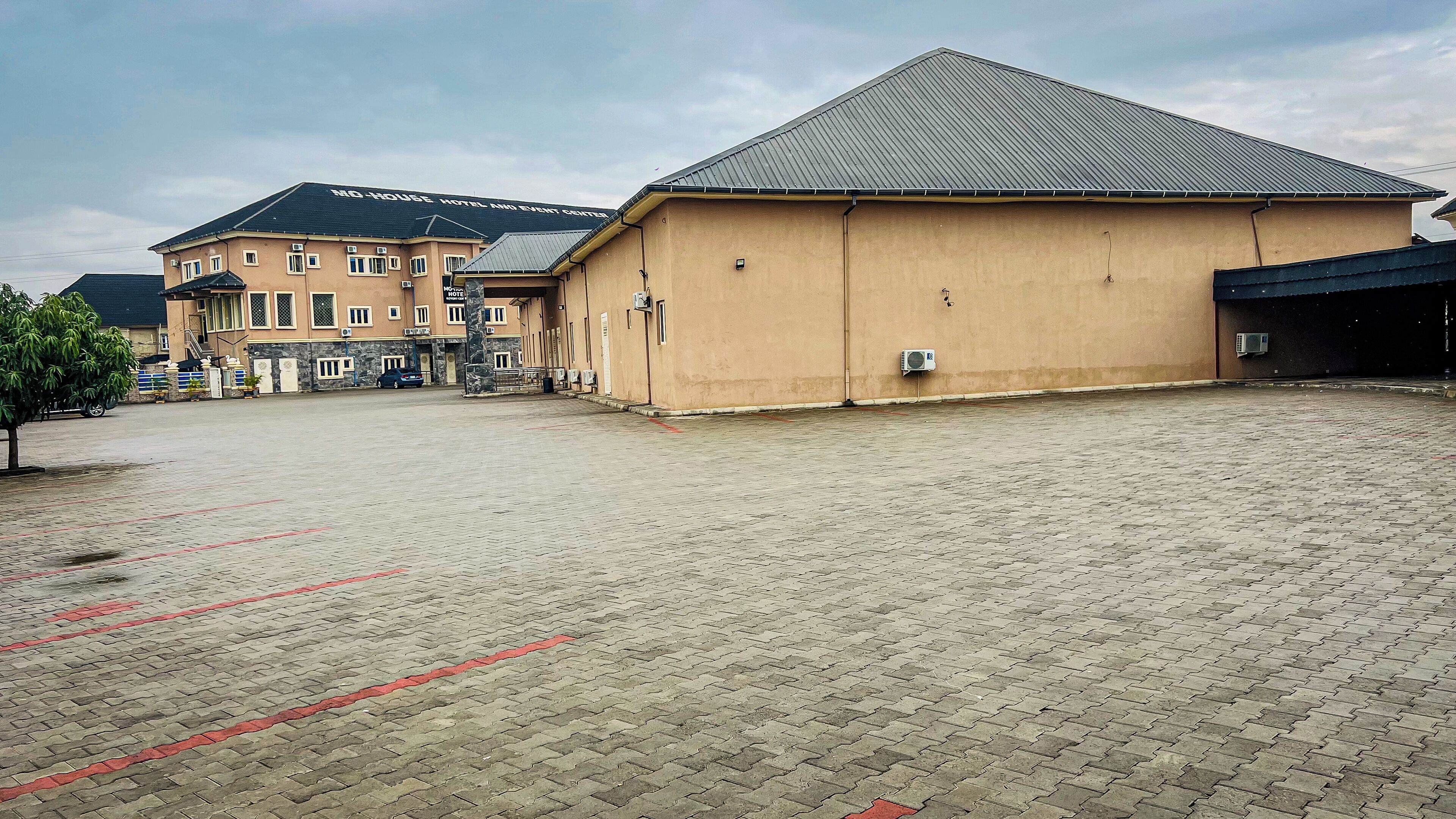 Un hôtel doté d’une cour dallée, d’un grand bâtiment à toit plat et d’une construction plus petite à toit en pente.