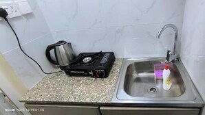 Una cocina con encimera de granito, estufa a gas, hervidor y pileta con grifo.
