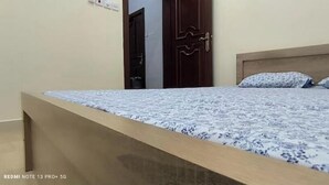 Ein Schlafzimmer mit einem Bett, einem Holzkopfteil und einer Tür im Hintergrund.