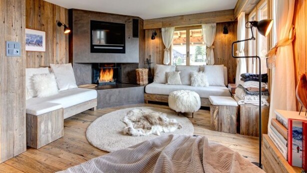 A cozy cabin-style room with a fireplace, wooden walls, and a large window. - 220sqm duplex luxury in the heart of Verbier (Val de Bagnes)