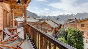 A wooden chalet with a balcony overlooking a mountain village and snow-capped peaks. - 220sqm duplex luxury in the heart of Verbier (Val de Bagnes)