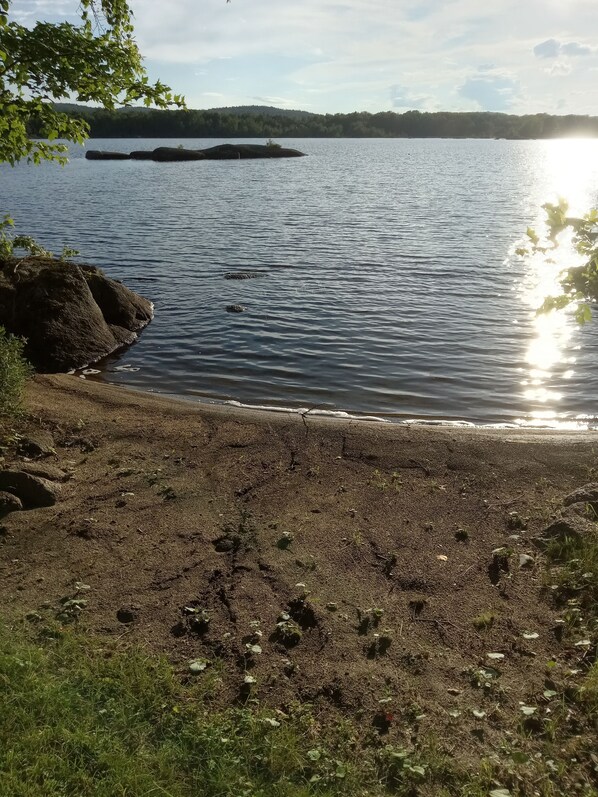A lakeside view with a rocky shoreline, calm water, and distant land. - Newly Renovated Cabin on a Private Lake Great for a Romantic Getaway or some R&R (Second Eel River Lake)