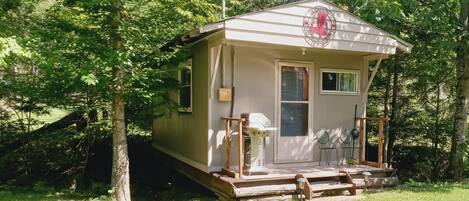 A small cabin with a porch, a window, and a door.