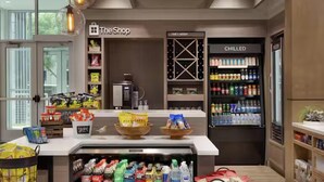A shop area with shelves stocked with snacks and beverages, a refrigerated section labeled "CHILLED," and a coffee machine. - Hilton Garden Inn Austin Central (Austin)