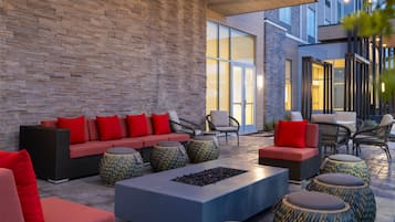 An outdoor seating area with a brick wall, sofas, chairs, and a fire pit.