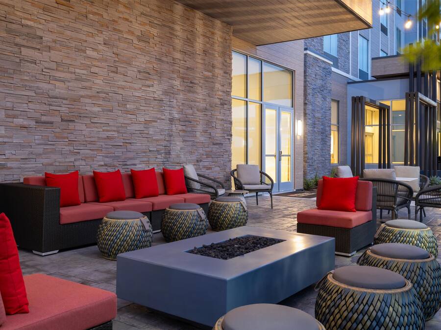 An outdoor seating area with a brick wall, sofas, chairs, and a fire pit.