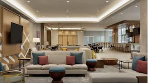 A spacious living area with a sofa set, coffee table, and a flat-screen TV mounted on the wall. - Hilton Garden Inn Austin Central (Austin)