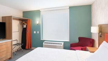 A hotel room with a bed, a wardrobe, a chair, a desk, and a television.