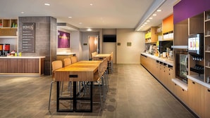 A modern hotel lobby with a reception desk, seating area, and kitchen facilities. - Home2 Suites by Hilton Bozeman Midtown (Bozeman)