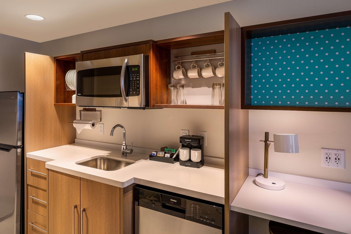 A modern kitchen with a stainless steel refrigerator, a built-in microwave, a coffee maker, and a dishwasher.