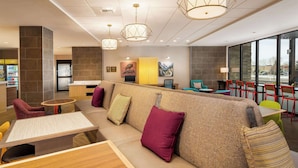 A modern lounge area with a sofa, chairs, tables, and a bar area. - Home2 Suites by Hilton Bozeman Midtown (Bozeman)