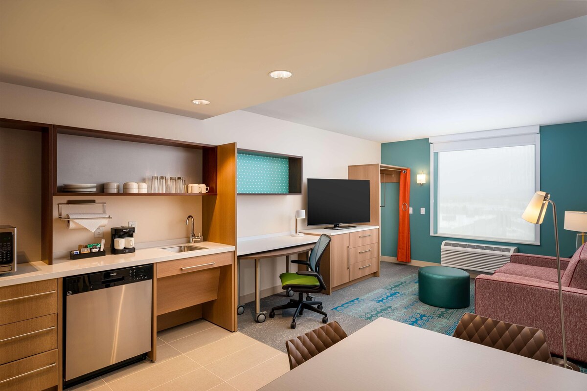 Une chambre d’hôtel compacte dotée d’une kitchenette, d’un téléviseur à écran plat, d’un canapé et d’un coin repas.