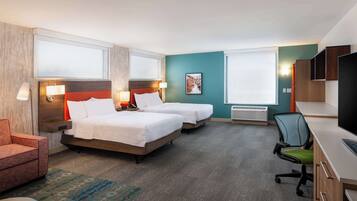 A hotel room with two beds, a desk, a chair, a TV, and a window.