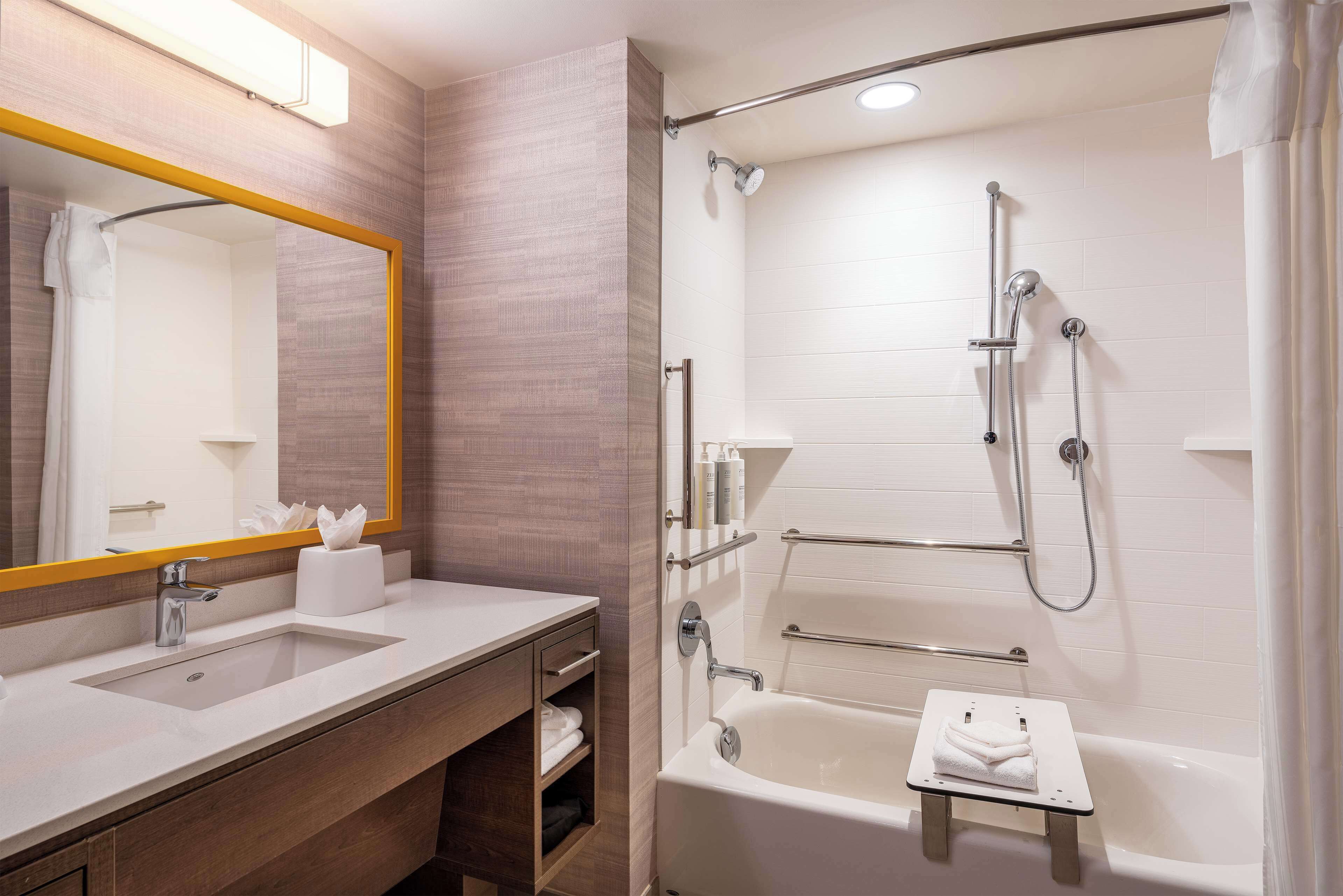 A modern bathroom with a large mirror, a sink, a bathtub, and a shower.