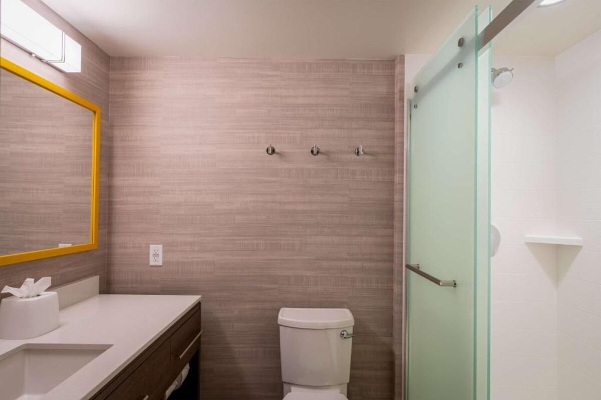 A bathroom with a toilet, a sink, a mirror, and a shower area.