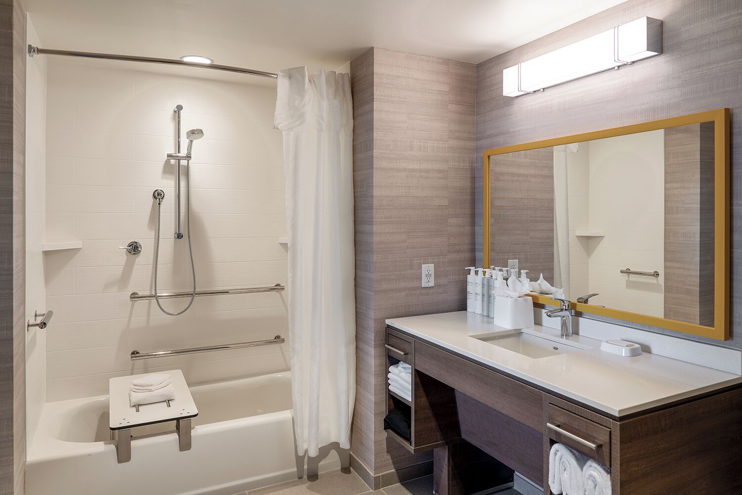 A modern bathroom with a walk-in shower, a bathtub, a vanity with a large mirror, and a towel rack.