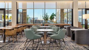 A modern hotel lobby with large windows, multiple seating areas, and a view of the cityscape. - Homewood Suites By Hilton North Las Vegas Speedway (North Las Vegas)