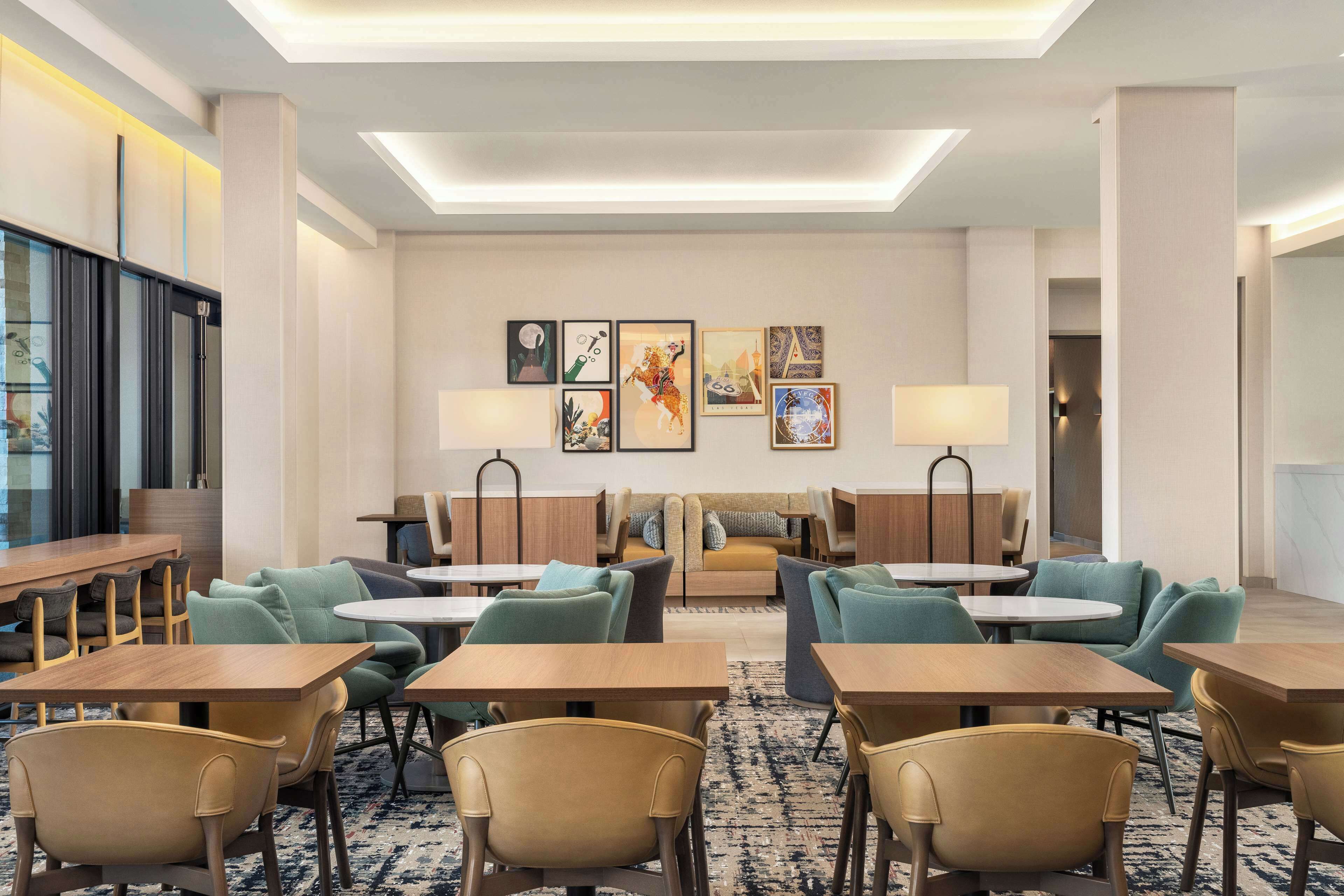 A hotel lobby with a central seating area, tables, and artwork on the walls.