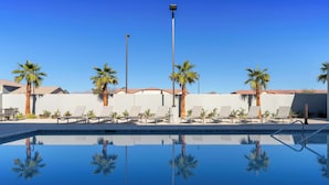A clear pool with lounge chairs and palm trees, surrounded by a white wall and a clear blue sky. - Homewood Suites By Hilton North Las Vegas Speedway (North Las Vegas)
