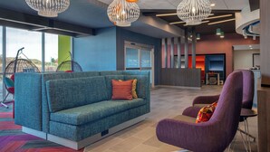 A modern lobby with a blue sofa, purple armchair, and unique pendant lights. - Tru By Hilton Anderson (Anderson)