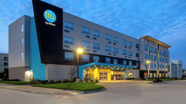 A modern hotel building with a prominent 'tru by Hilton' sign, multiple floors, and a well-lit entrance area. - Tru By Hilton Anderson (Anderson)