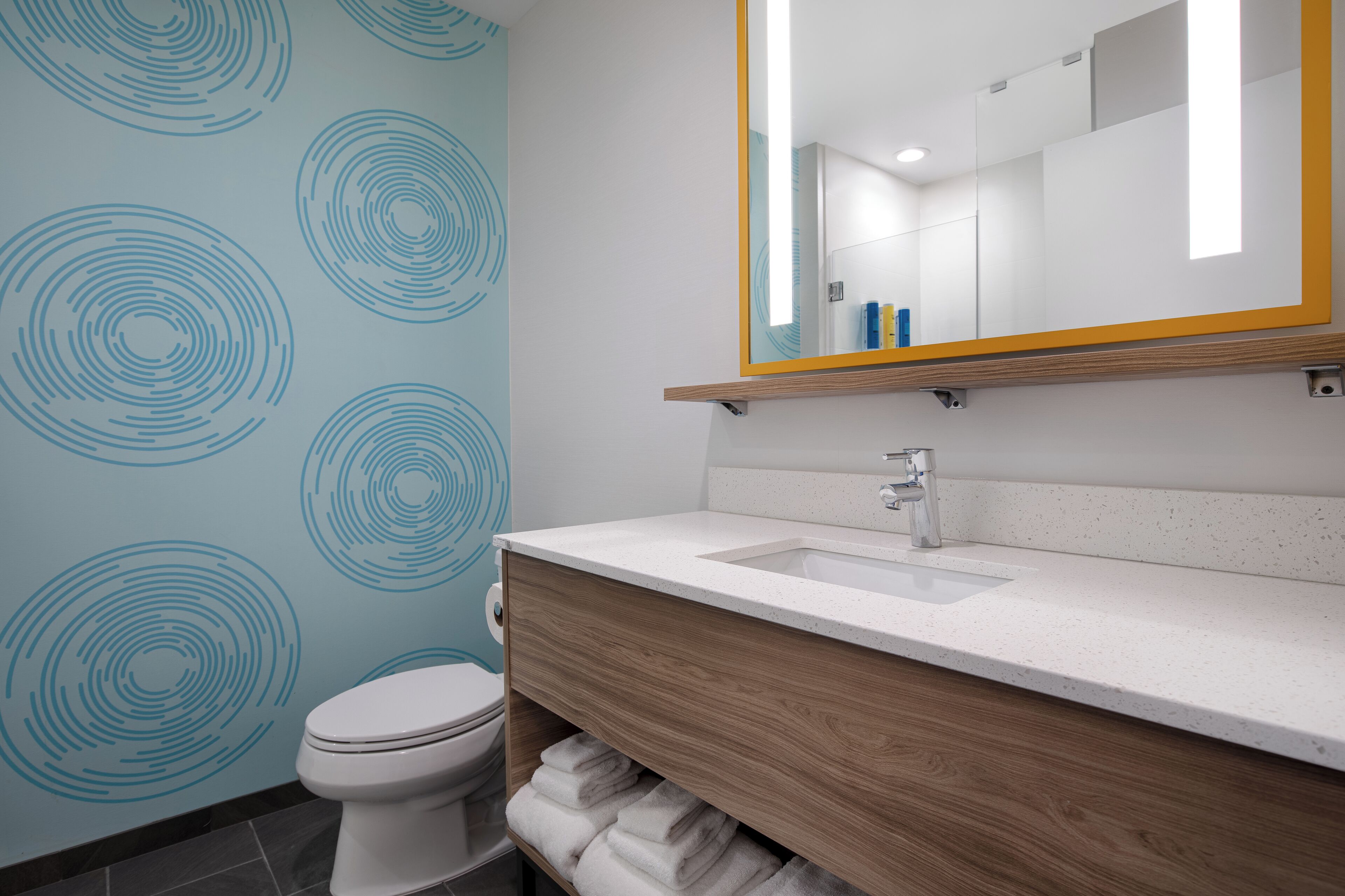 A modern bathroom with a white sink, wooden vanity, and a toilet.