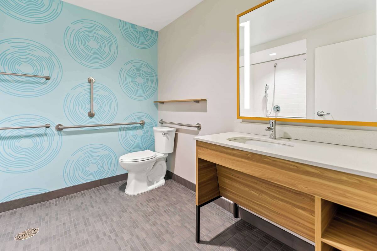 A modern bathroom with a toilet, sink, and mirror.