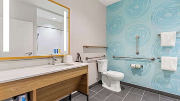 A modern bathroom with a wooden vanity, a large mirror, a toilet, and a towel rack.